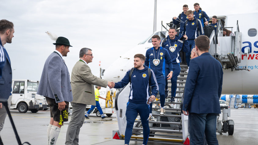 Staatsminister Dr. Florian Herrmann begrüßt die schottische Fußball-Nationalmannschaft am Flughafen München.