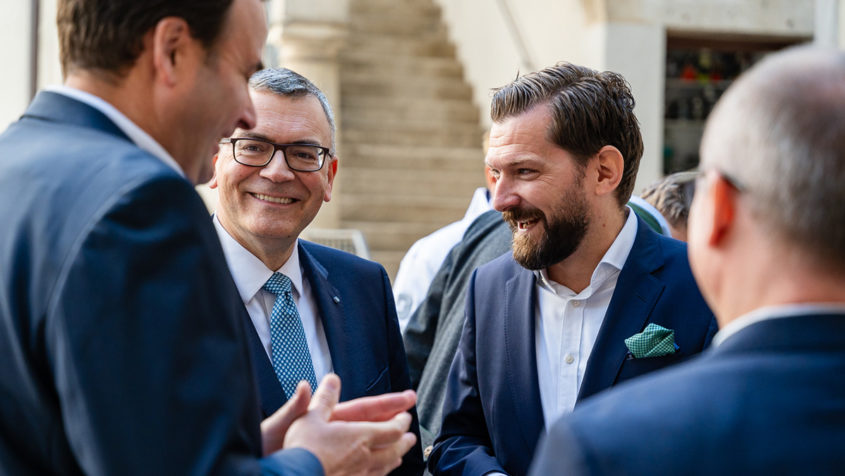 Beim Mittagsempfang des Bundesverbands der Systemgastronomie e.V. kommt Staatsminister Dr. Florian Herrmann unter anderem mit dem Hauptgeschäftsführer des Bundesverbands der Systemgastronomie e.V., Markus Suchert, und weiteren Gästen ins Gespräch. © BdS/Nadine Ingold